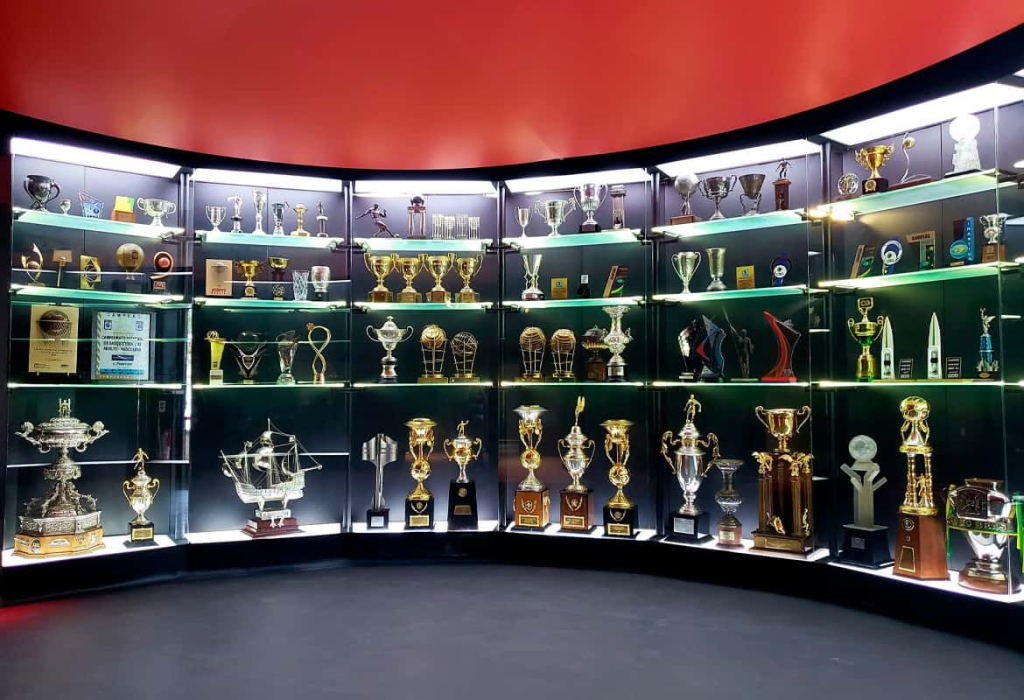 Interior view of Flamengo's trophy room at the club museum, showcasing numerous trophies and memorabilia in glass cases.