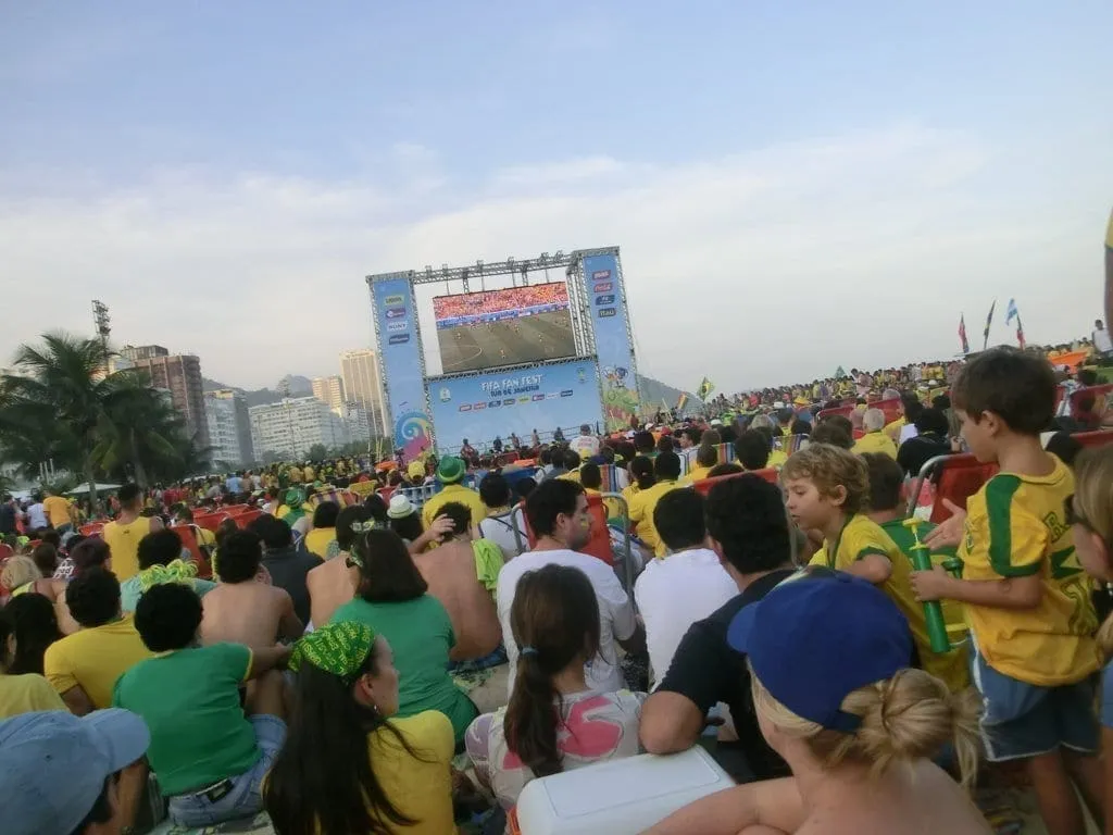 Crowd wearing Brazil colors watching a World Cup match on a big screen at the beach in Rio de Janeiro.